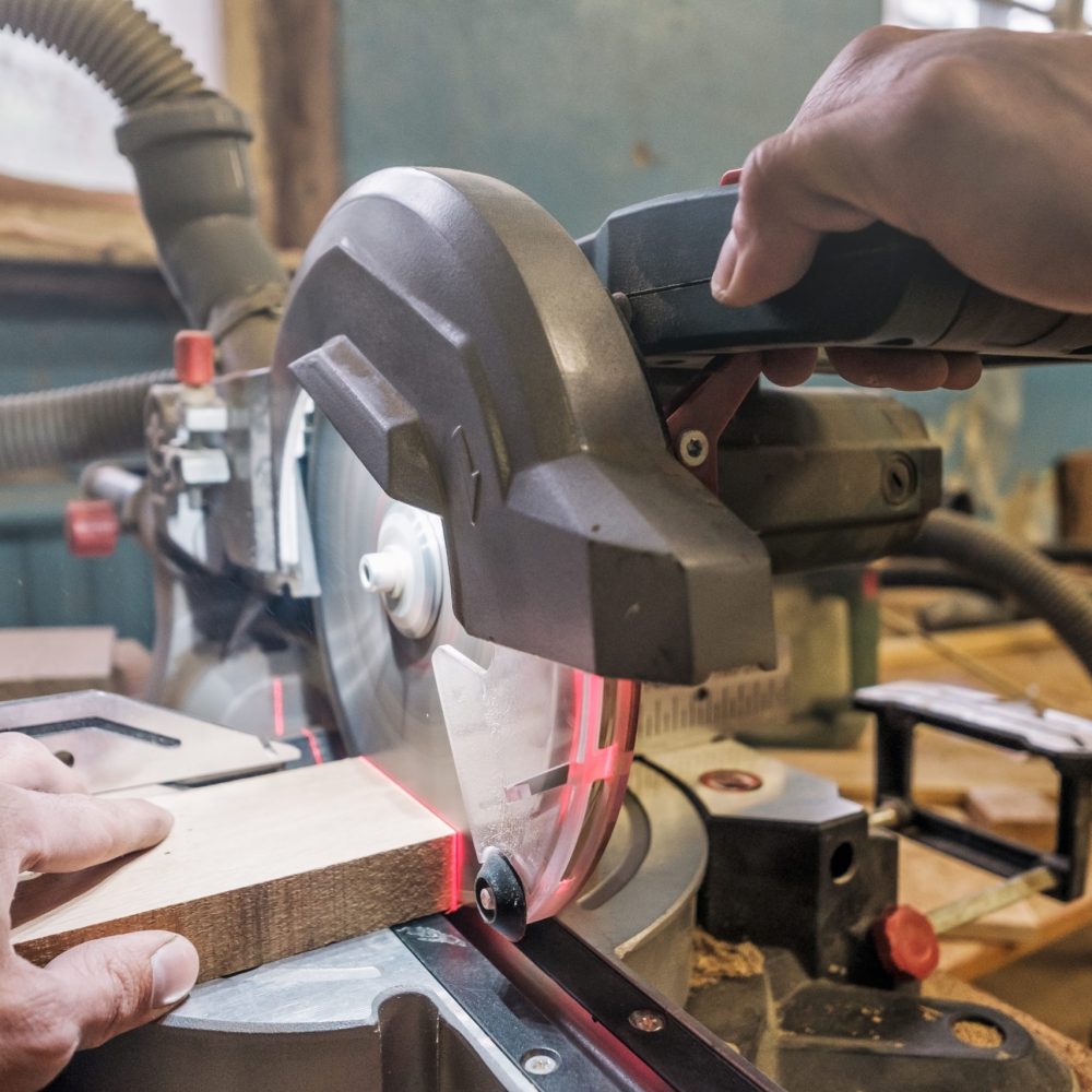 Caucasian man carpenter worker working driving circular saw to cut boards on a new furniture detail.